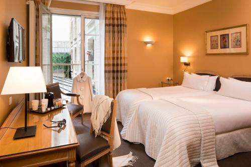 a hotel room with a bed and a desk and a window at Le Littré in Paris