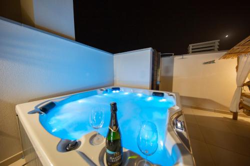 a blue bath tub with a bottle and two wine glasses at MEDANO4YOU Tina's Jacuzzi Terrace Playa Chica in El Médano