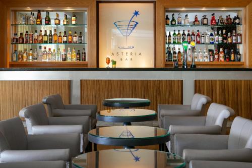 a bar with tables and chairs and alcohol bottles at Atlantica Miramare Beach in Limassol