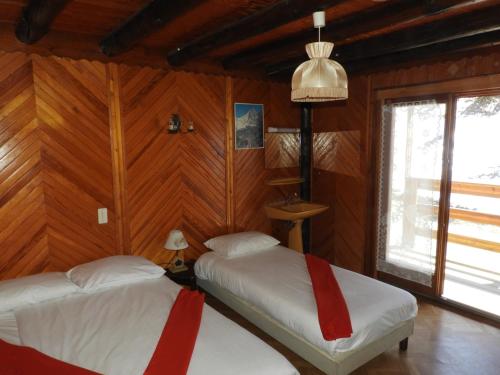 Duas camas num quarto com paredes com painéis de madeira em 1 Authentique chalet, le Mirador em Les Gets