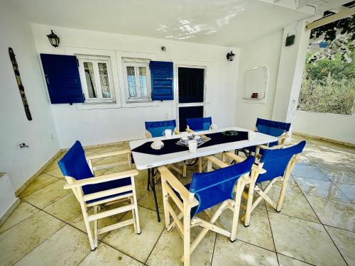 a dining room with blue chairs and a table at Villa Arietta Santorini in Perissa