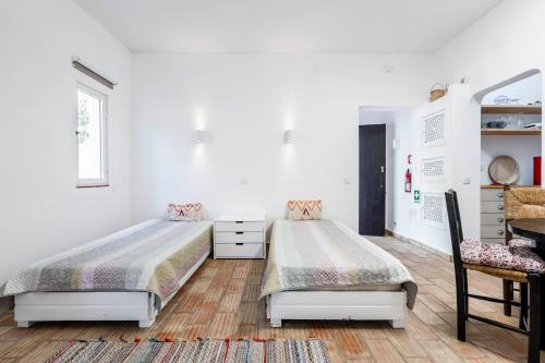 Apartamento 157, Pedras d’el Rei في تافيرا: سريرين في غرفة نوم بجدران بيضاء وأرضية خشبية