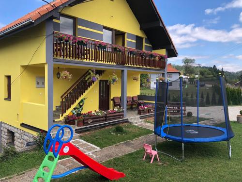 una casa con parque infantil frente a una casa en Apartmani NINA Zlatar, en Nova Varoš