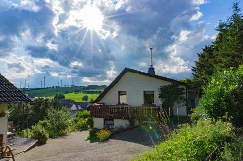 Une petite maison blanche avec le soleil dans le ciel dans l'établissement Ferienhaus ROSENHOF Vulkaneifel, à Ormont
