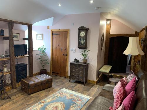 a living room with a couch and a clock on the wall at Brecon Boutique Breaks River Run in Sennybridge