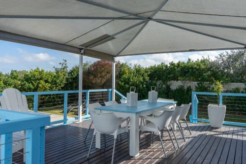 a deck with a blue table and chairs under a white umbrella at Blue Star Villa in Tergniet