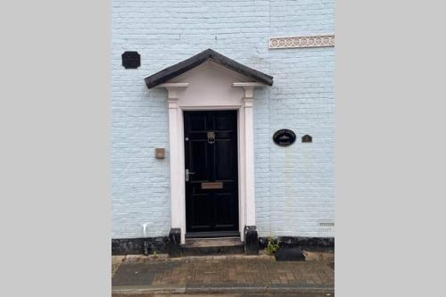 a black door on a white brick building at City Centre Entire Studio Apartment in Chichester