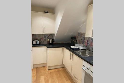 a kitchen with white cabinets and a sink at City Centre Entire Studio Apartment in Chichester