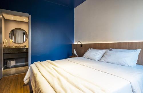a bedroom with a large bed with a blue wall at Swan Generation Porto Alegre in Porto Alegre
