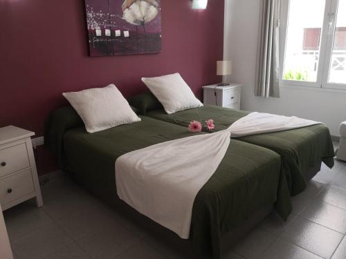 a bedroom with a bed with green and white sheets at Apartamentos El Guirre in Valle Gran Rey