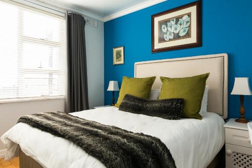 a bedroom with blue walls and a bed with green pillows at Entire 5 Bedroom 5 Bathroom Sea Point Villa with Secure Parking in Cape Town