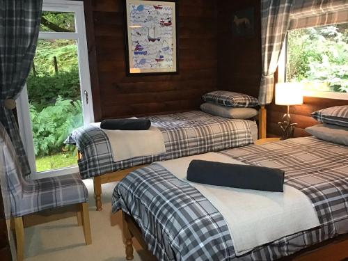a bedroom with three beds and a window at Fox Lodge Traditional Log Cabin in Dunoon