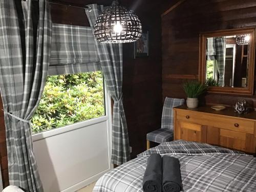 a bedroom with a bed and a window at Fox Lodge Traditional Log Cabin in Dunoon
