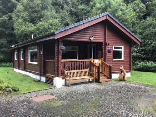a log cabin with a porch and a bench at Fox Lodge Traditional Log Cabin in Dunoon
