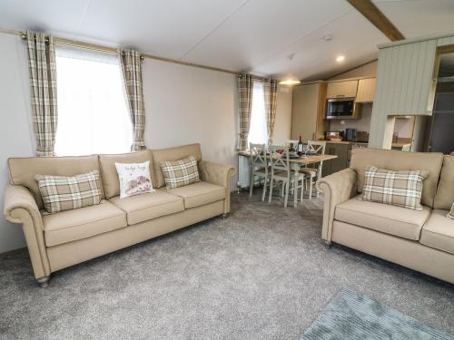 a living room with two couches and a kitchen at Hedgehog Lodge in Carnforth