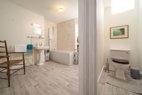 a bathroom with a tub and a toilet and a sink at Diana's Cottage in Braunton