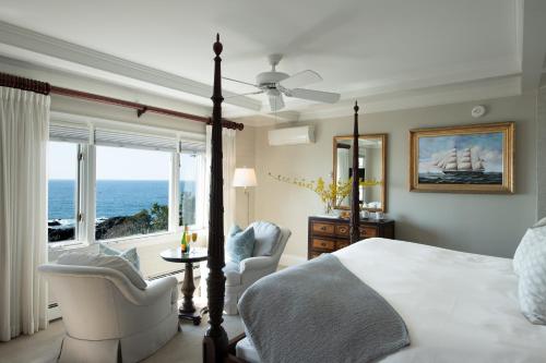 a bedroom with a bed and two chairs and a window at Cape Arundel Inn and Resort in Kennebunkport