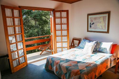 a bedroom with a bed and a door to a balcony at Chalé Belga em condomínio - 1,2 km do Centro Turístico Capivari in Campos do Jordão
