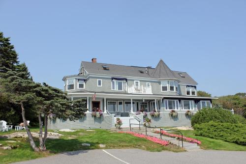 a large gray house with flowers in the front yard at Cape Arundel Inn and Resort in Kennebunkport