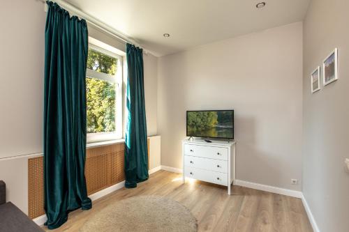 een woonkamer met een televisie en een raam bij à la fontaine in Druskininkai