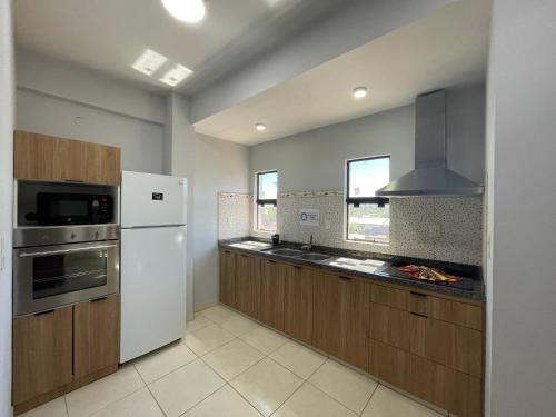 a kitchen with a white refrigerator and wooden cabinets at WilMar Apart Hotel in Encarnación