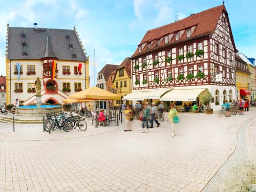 a group of people walking in a street with buildings at Hotel Tuchhaus in Volkach