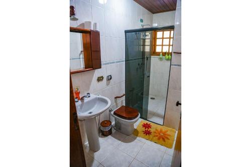 a bathroom with a shower and a toilet and a sink at Chalé Belga em condomínio - 1,2 km do Centro Turístico Capivari in Campos do Jordão