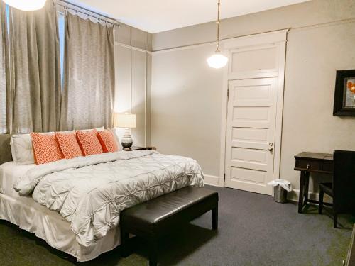 a bedroom with a bed with orange pillows and a desk at The Loft on the Square in Magnolia