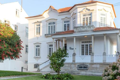 a white house with a tree in front of it at The Luggage in Coimbra
