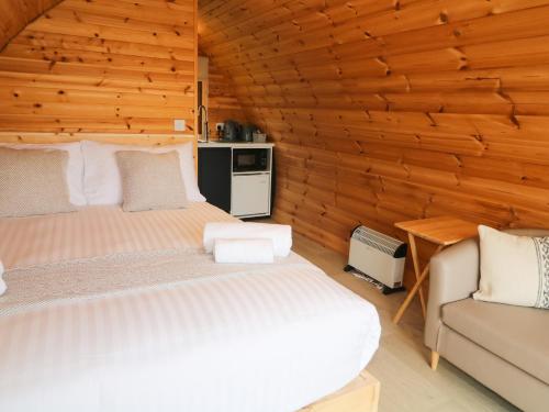 two beds in a room with wooden walls at Pod 3 in Ballymoney