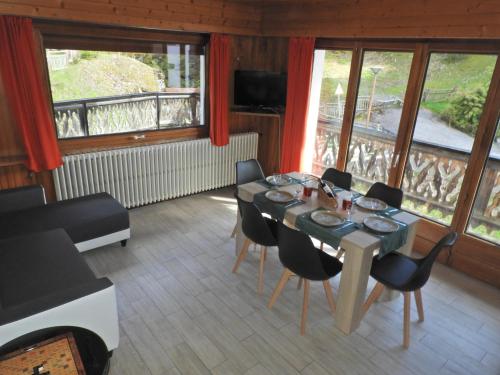 une salle à manger avec une table, des chaises et des fenêtres dans l'établissement Manoir 2, aux Gets
