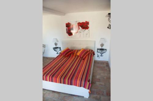 1 dormitorio con 1 cama con una manta a rayas de colores en Studio indépendant dans mas provencal, en Le Rouret