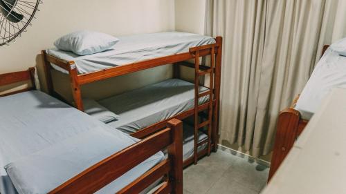 two bunk beds in a room with a curtain at Hostel Paraíso in Arraial do Cabo
