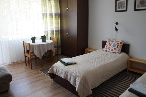 a bedroom with a bed and a table with a chair at Mildos butas in Birštonas