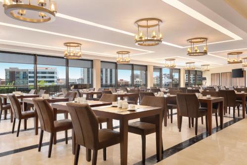 een restaurant met tafels en stoelen en grote ramen bij Days Hotel by Wyndham Istanbul Maltepe in Istanbul