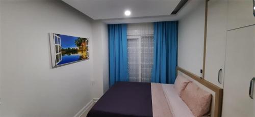 a small bedroom with blue curtains and a bed at GUL APART ANTALYA in Aksu