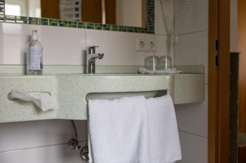 ein Badezimmer mit einem weißen Handtuch, das von einem Waschbecken hängt in der Unterkunft Hotel Garni Lehrertal in Ulm