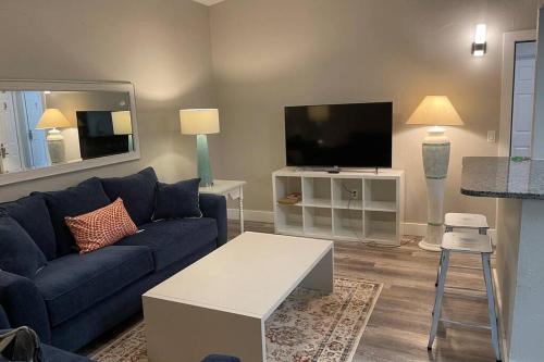a living room with a blue couch and a flat screen tv at Siesta Key Village-Suite #4: A block to the Beach! in Sarasota