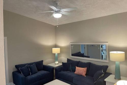 een woonkamer met twee blauwe banken en een plafondventilator bij Siesta Key Village-Suite #4: A block to the Beach! in Sarasota