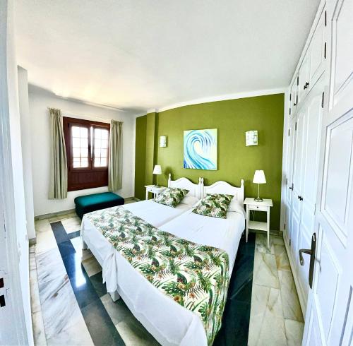 a bedroom with a large bed and a green wall at Apartamentos Tapahuga in Playa de Santiago
