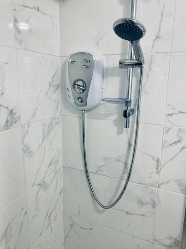 a shower in a white tiled bathroom with a blow dryer at Glasgow City Centre Flat with River Views and Parking in Glasgow