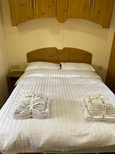 Zwei Handtücher liegen auf einem weißen Bett. in der Unterkunft Charming two bedroom static caravan in whithorn in Newton Stewart