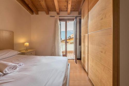um quarto com uma cama branca e uma porta para uma varanda em il borgo appartamenti con parcheggio em Malcesine