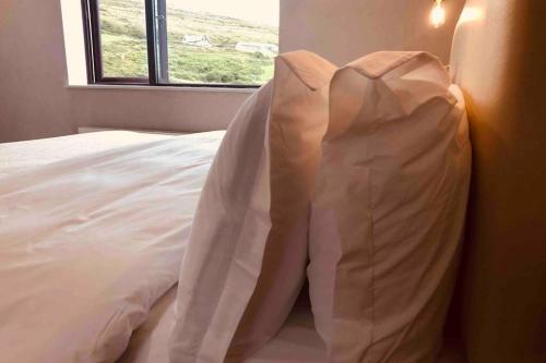 a bed with white sheets and a window at Wild Atlantic Way Apartment in Fanore