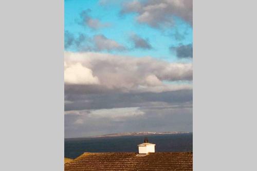 a lighthouse on top of a roof with a cloudy sky at Wild Atlantic Way Apartment in Fanore