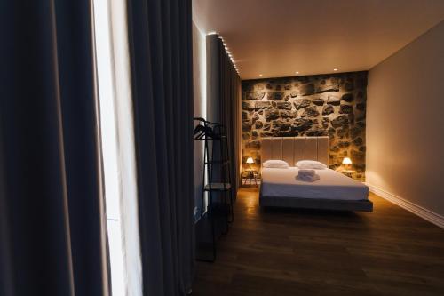 a bedroom with a bed and a stone wall at CITY STONE HOUSE in Ponta Delgada