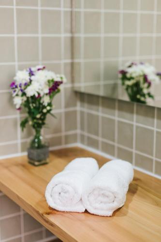 two towels on a wooden table with a vase of flowers at CITY STONE HOUSE in Ponta Delgada