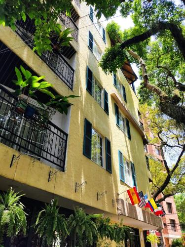 a tall yellow building with windows and trees at Casa del Hidalgo Hotel Cali Centenario in Cali