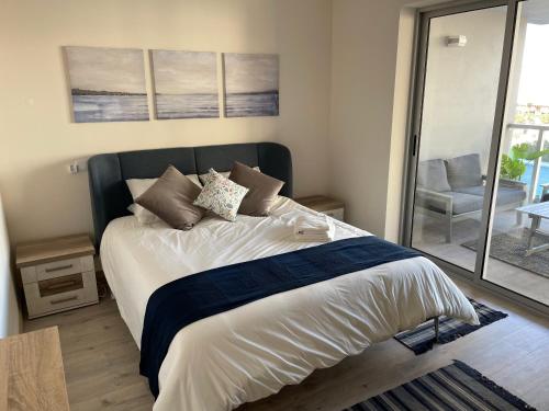 a bedroom with a bed and a balcony with a chair at Algarve Sun Apartment in Portimão