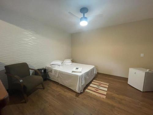 a room with a bed and a chair and a ceiling fan at Suites da Cabana in Lumiar